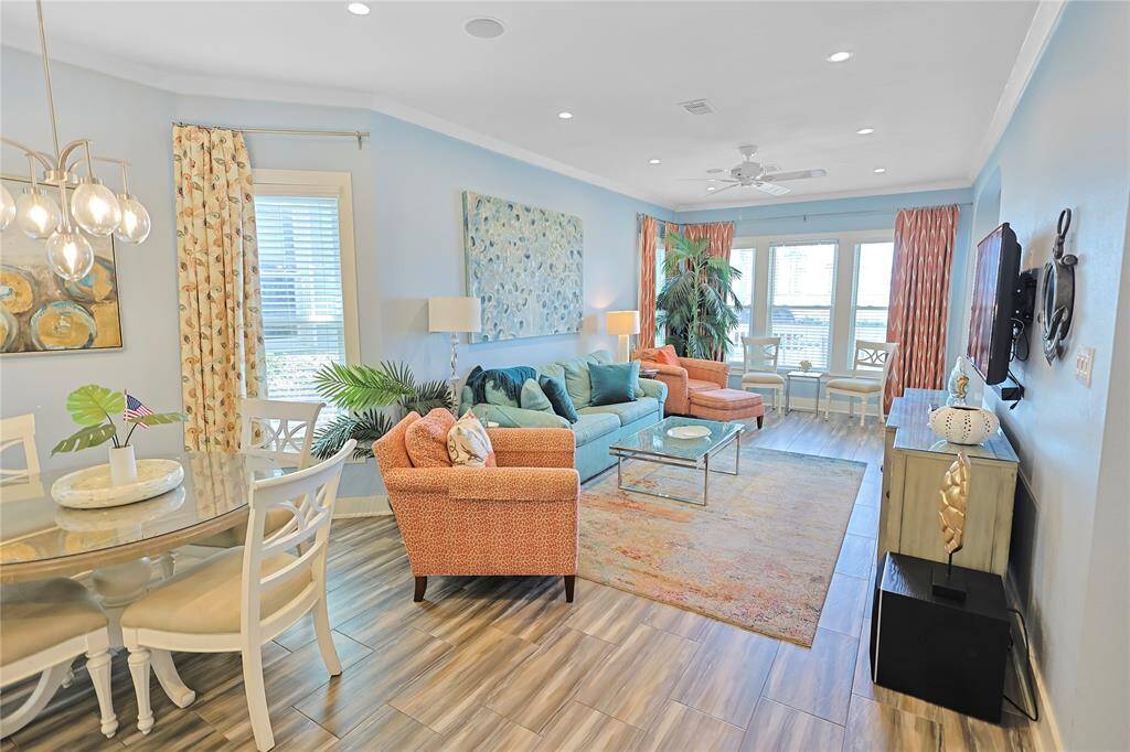 This bright, open-concept living and dining area features modern furnishings with a mix of vibrant colors- large windows allow ample natural light, perfect for comfortable and stylish living.