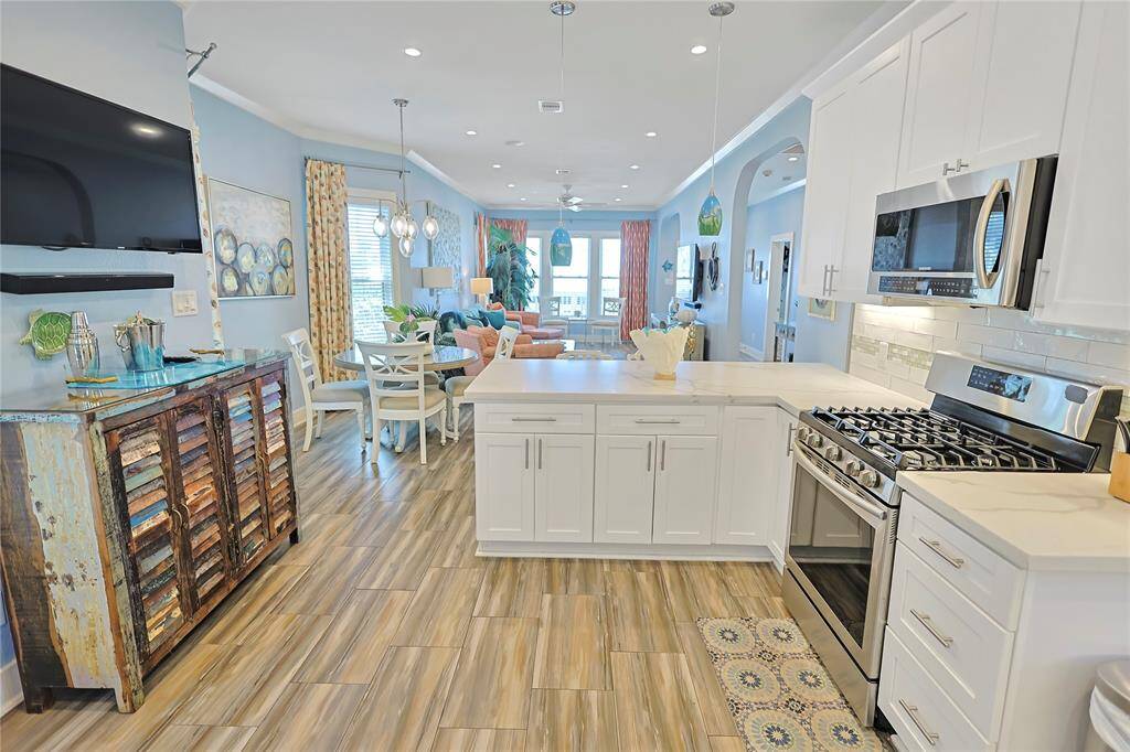 This bright and inviting modern kitchen features stainless steel appliances, white cabinetry, and a large island- perfect for entertaining.