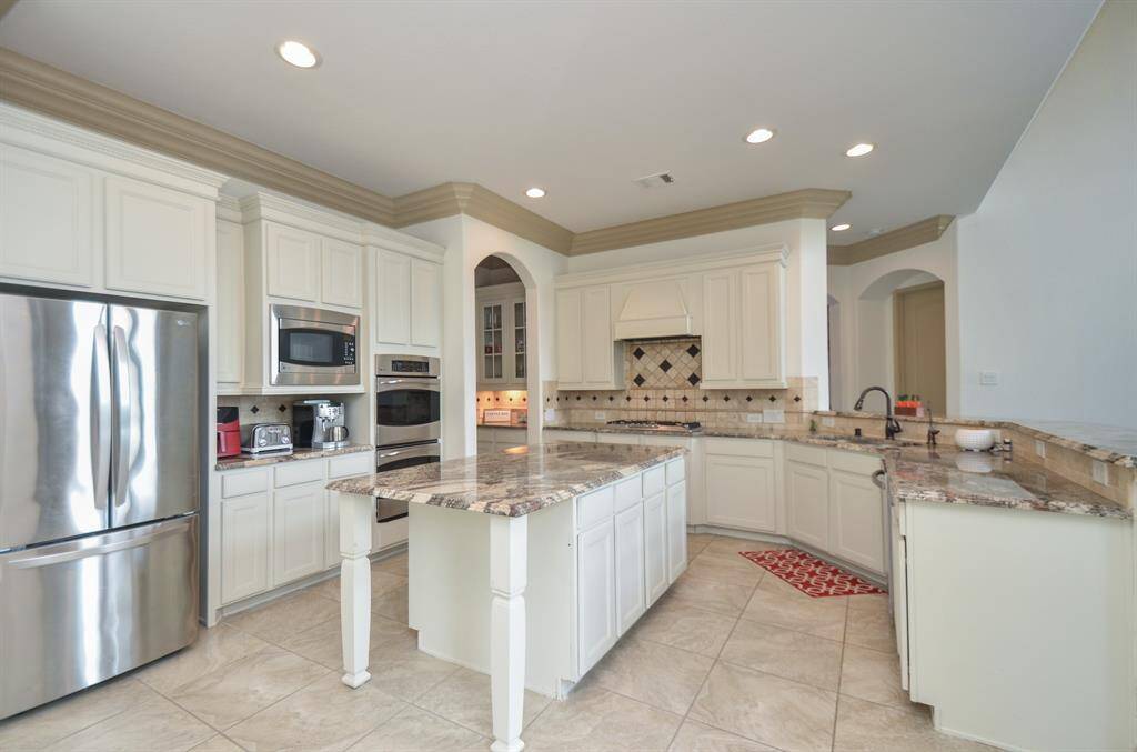 There's just something warm and inviting about a primarily white kitchen, or bathroom, for that matter. This amazing chef's kitchen is any cook's/host's dream 'workshop'!  Tons of cabinetry (up and down) line this special kitchen, with gorgeous granite? quartz? countertops and detailed tile backsplash wherever your tasks take you!