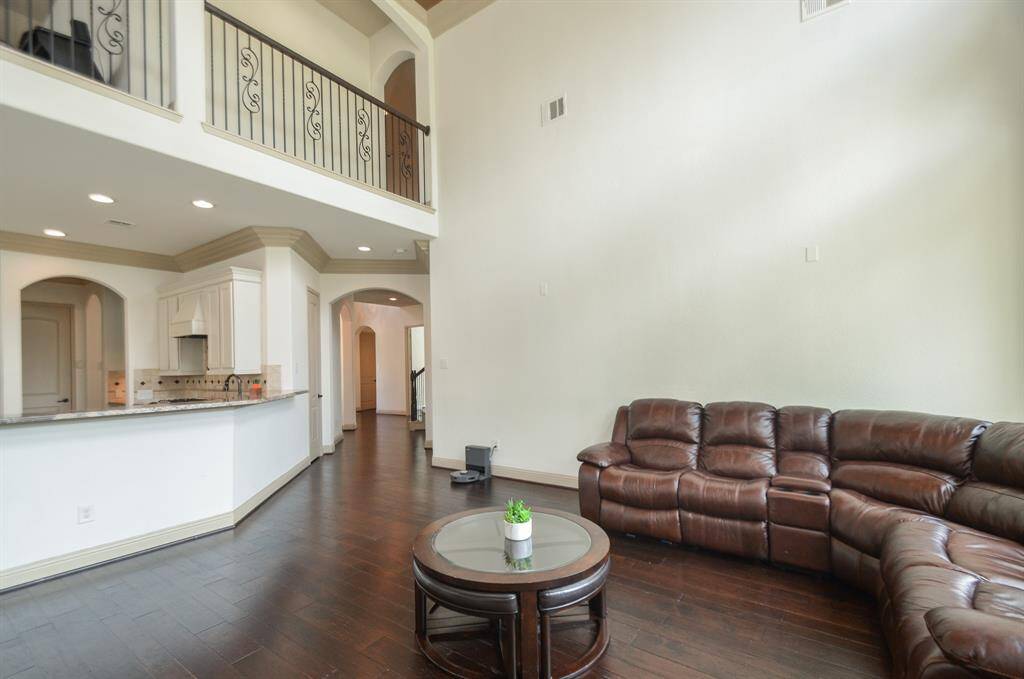 What a completely satisfying view, top to bottom, of this wide open, airy space, comprised of living area, kitchen (left), with a view of the catwalk/railing on the 2nd floor.