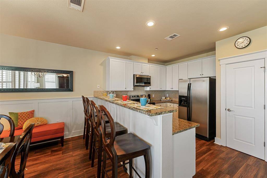 This cheerful kitchen is equipped with granite countertops, crisp white cabinetry, and stainless steel appliances—blending style and practicality.