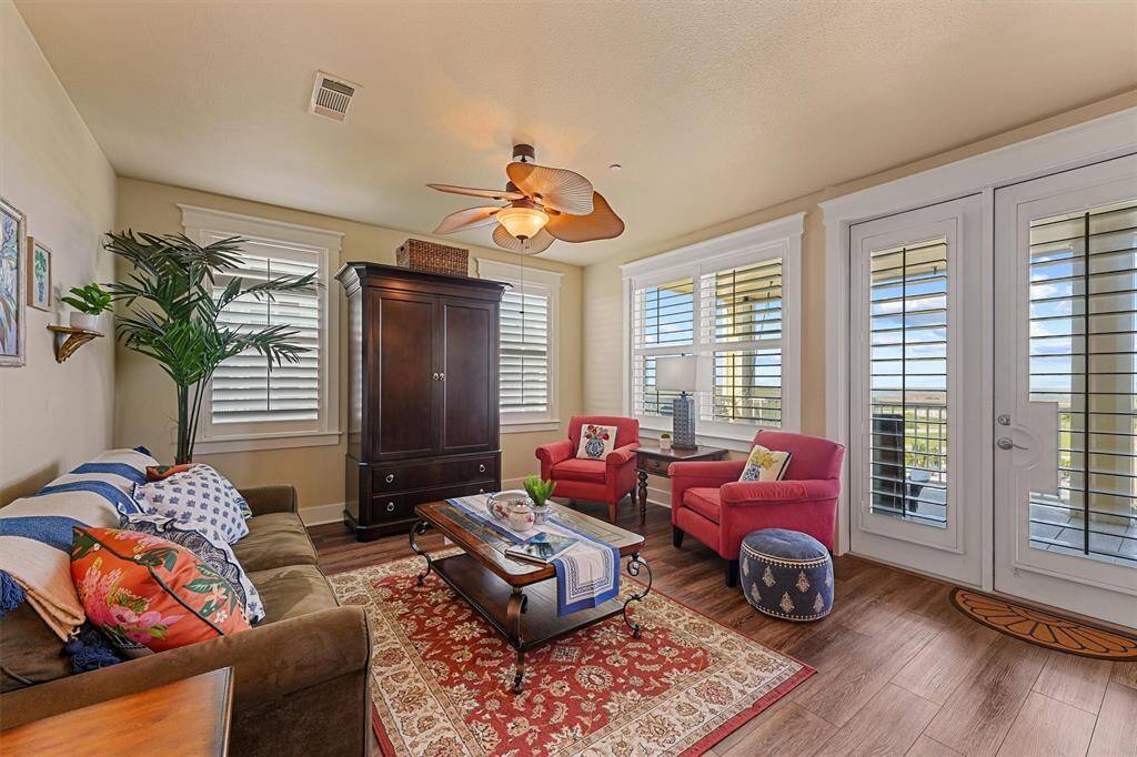 The inviting living room features charming coastal decor, rich wood tones, and beautiful natural light—offered fully furnished for a seamless move-in or turnkey rental.