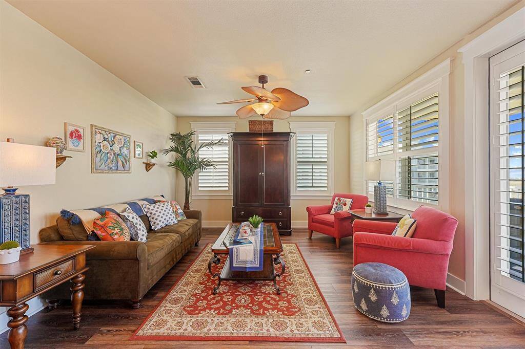 Shuttered windows and glass doors fill the space with sunlight while offering peaceful views and access to the spacious balcony just beyond.