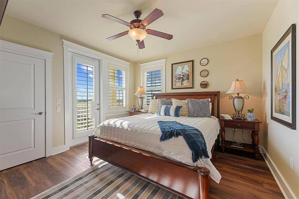 Wake up to serene views in this sunlit primary suite, complete with private balcony access, rich wood-look flooring, and a peaceful coastal vibe.