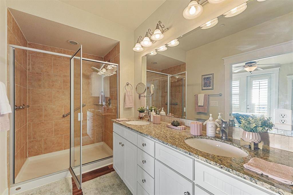The ensuite bath features a granite-topped dual vanity, oversized walk-in shower with tile surround, and thoughtful touches for everyday luxury.