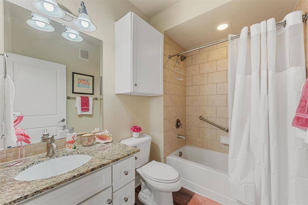The full guest bathroom includes a granite vanity, tile surround tub/shower combo, and built-in storage, blending function with a fresh coastal feel.