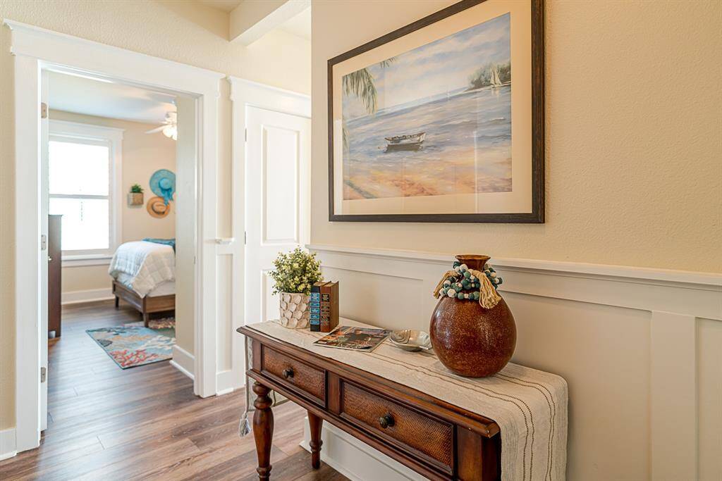 Step into a welcoming foyer with elegant wainscoting, new vinyl plank flooring, and a peek at the light-filled layout beyond. The laundry room is conveniently located just behind the double doors.