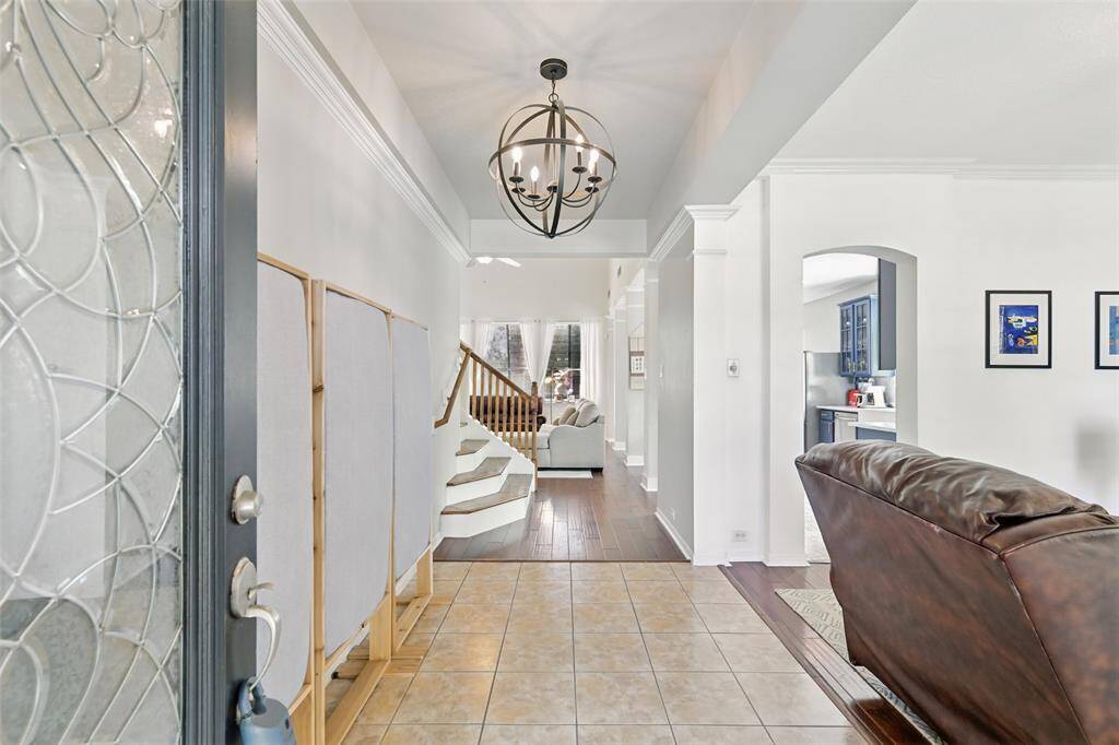 Step into the home through a beautifully crafted solid wood front door, adorned with elegant leaded glass. The entryway features timeless tile flooring, creating a welcoming first impression.