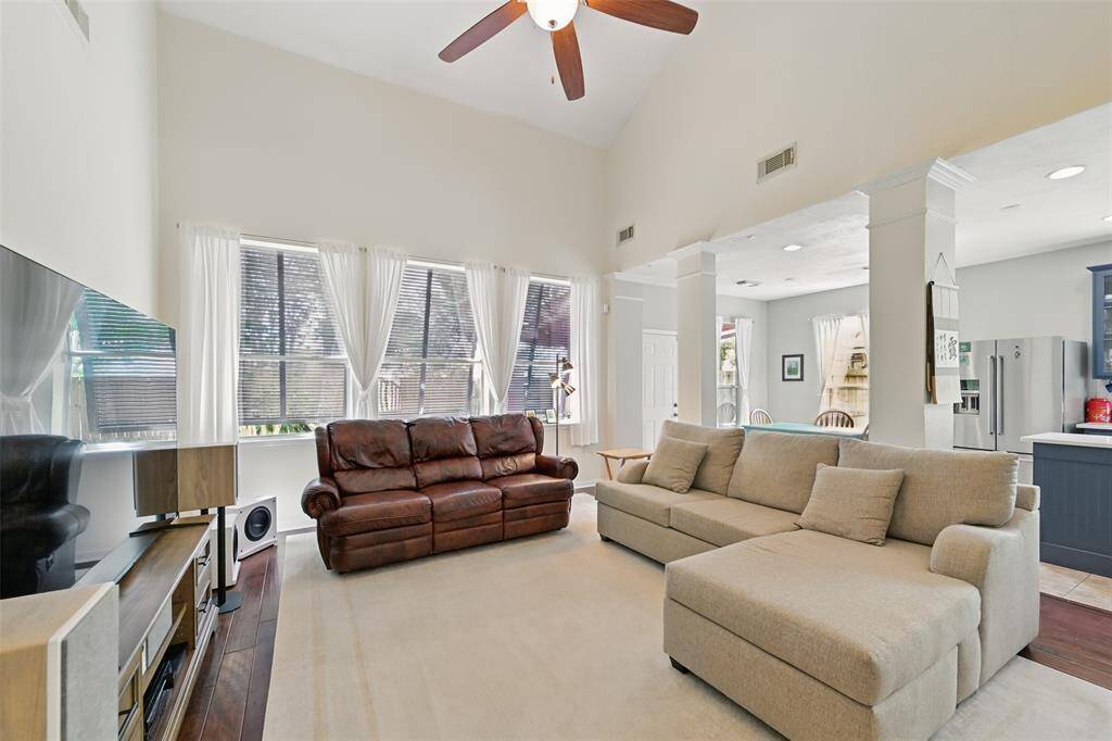 Open concept home. Family room with wood flooring is open to the kitchen. Columns with crown molding accents lead to the kitchen and breakfast room.