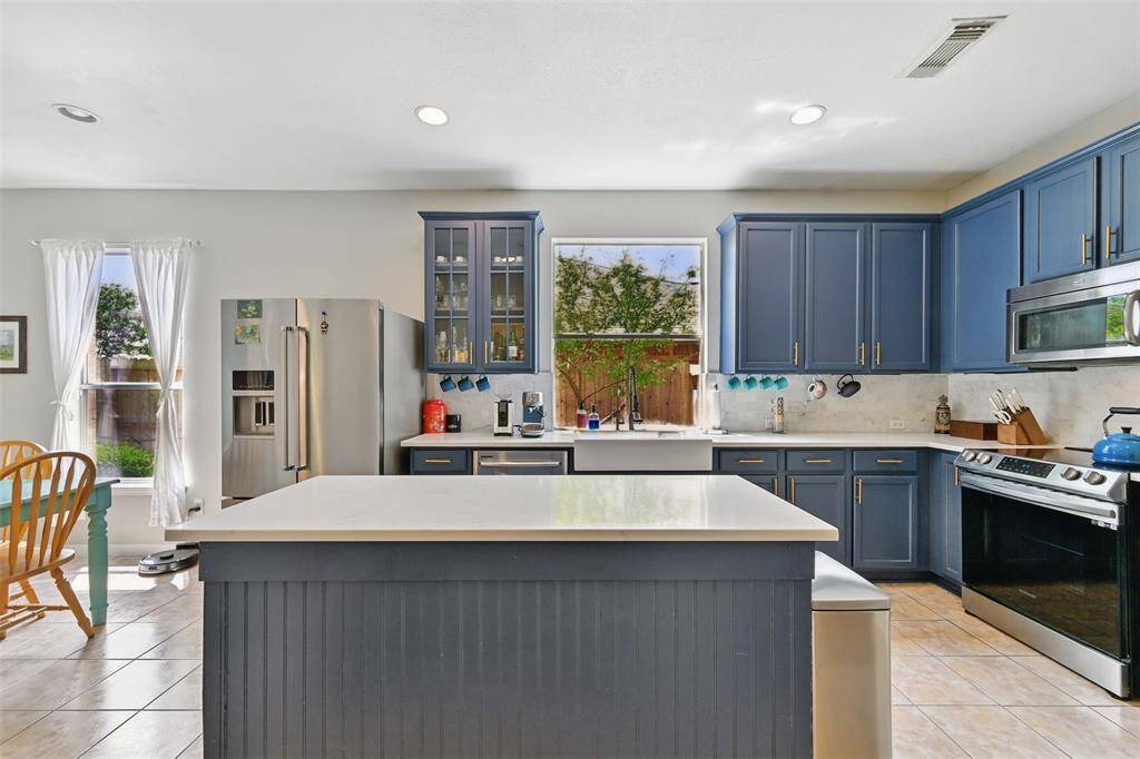 The kitchen features Silas Stone countertops and a spacious island, combining durability with elegance.