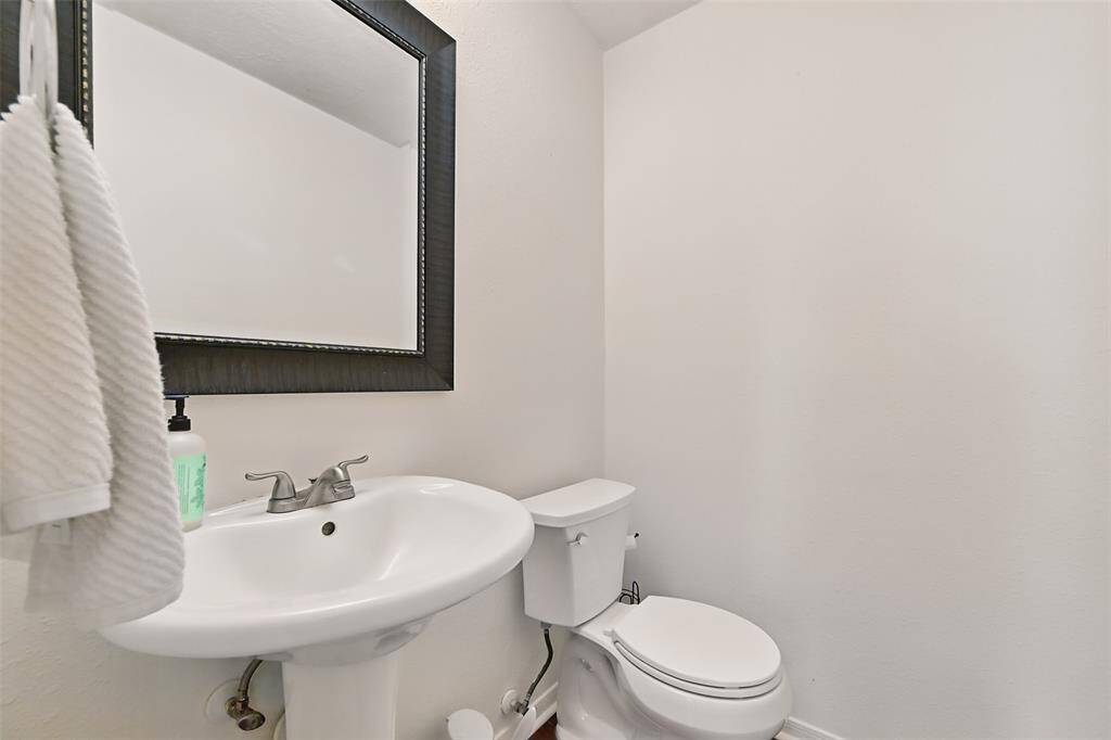 A conveniently located half bath on the lower level features a sleek pedestal sink and an elongated toilet, combining functionality with style.