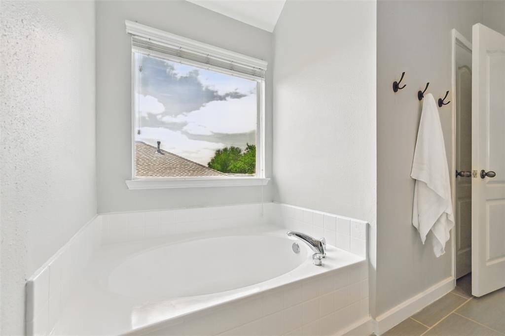 A soaker tub beautifully accented with ceramic tile and complemented by a window that invites an abundance of natural light.
