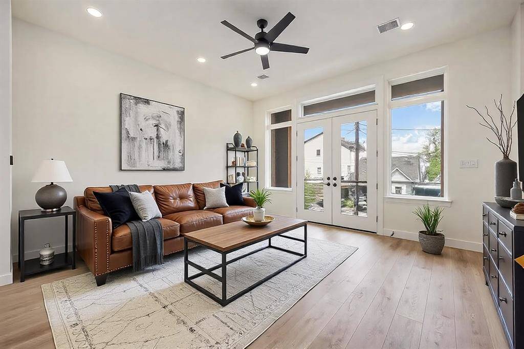 The living room takes in an abundance of natural light at the balcony doors and surrounding windows. *Virtually staged photo