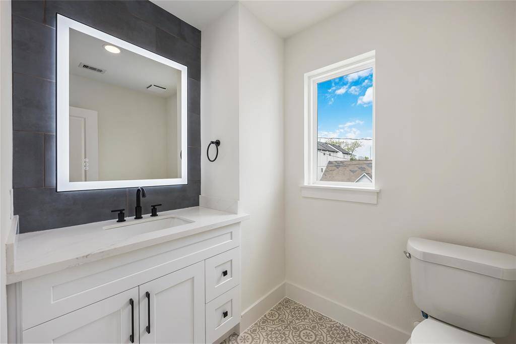 An elegant half-bath on the 2nd floor boasts a tile accent wall and a sophisticated light-up mirror.