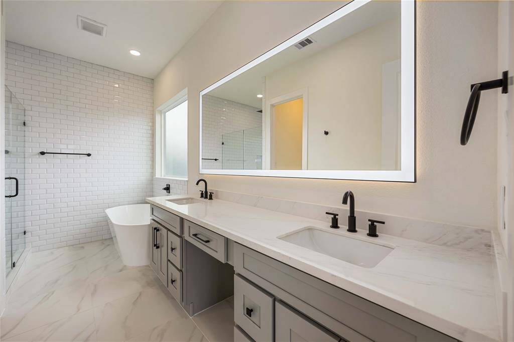 The primary bath shows the incredible amount of quartz-topped counter space on this dual-sink vanity. Notice the elegant subway tile back wall that continues around the sides of the shower.
