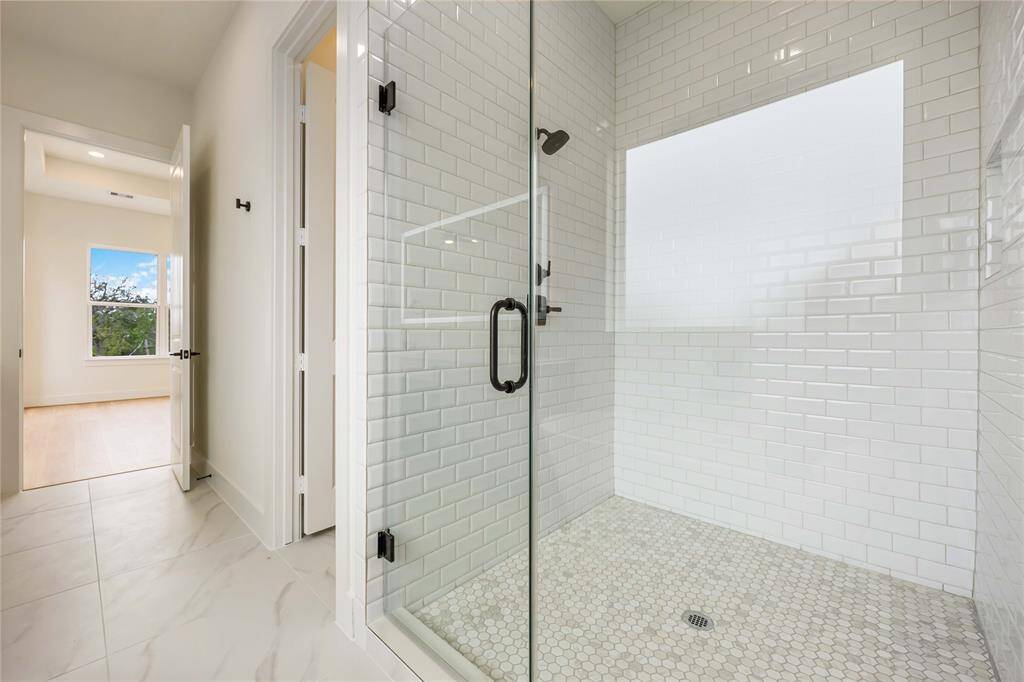 The subway tile extends to surround the frameless stand-alone shower in the primary bath.