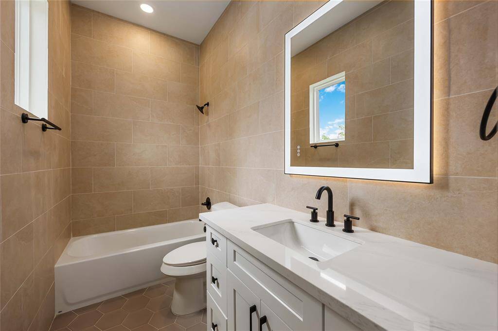 This gorgeous en-suite in Bedroom 3 features a tub and shower combination in tile surround and another lighted mirror.