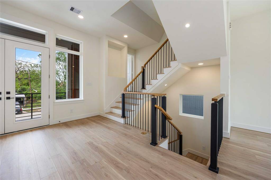 The second floor rests under soaring ceilings with plenty of natural light and recessed lighting. Notice the covered balcony just behind the French doors.