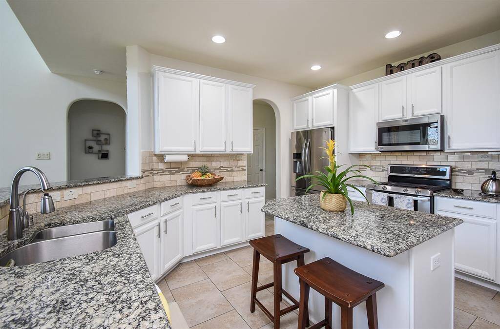 Beautiful, brick-like tile surround, with mosaic tile influence, creates the backsplash. Stainless steel appliances add to the glow of this bright space.