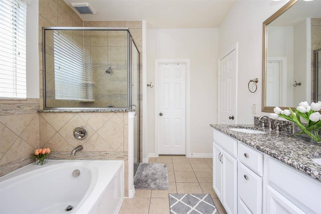 White cabinetry, walls and stunning earth tones on bath, shower surround and floor bring relaxation to the primary ensuite bath. Choose a long, lazy soak or a quick refreshing shower after move in day comes to a close!
