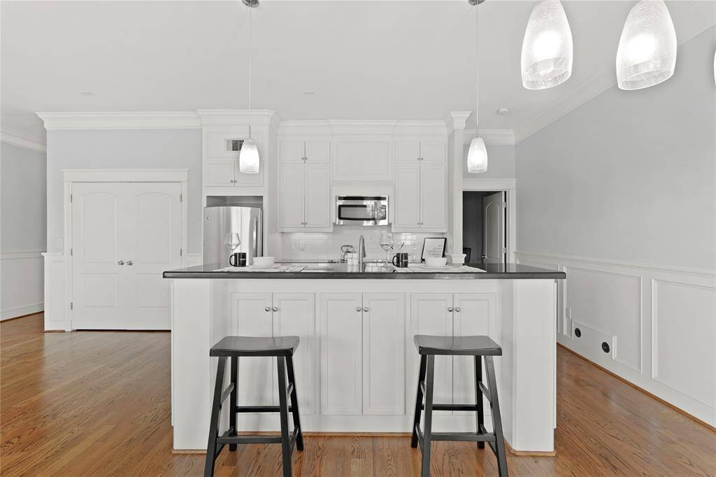 Central island with bar seating and pendant lighting. Island offers additional storage cabinets beneath the bar.  Area has a clean, bright aesthetic with ample storage.