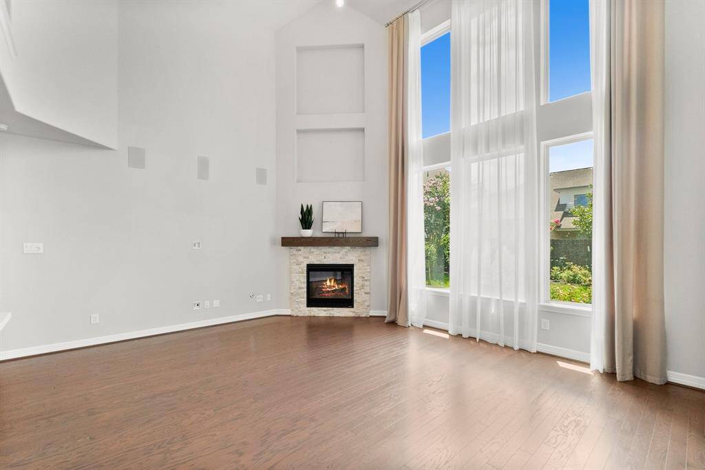 Family room features high ceilings, a wall of windows and a gas fireplace with wooden mantle