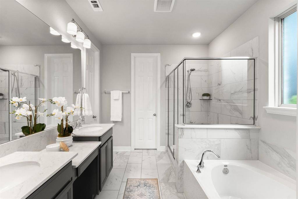 Primary bath features double sinks, a large soaking tub and glass shower with bench