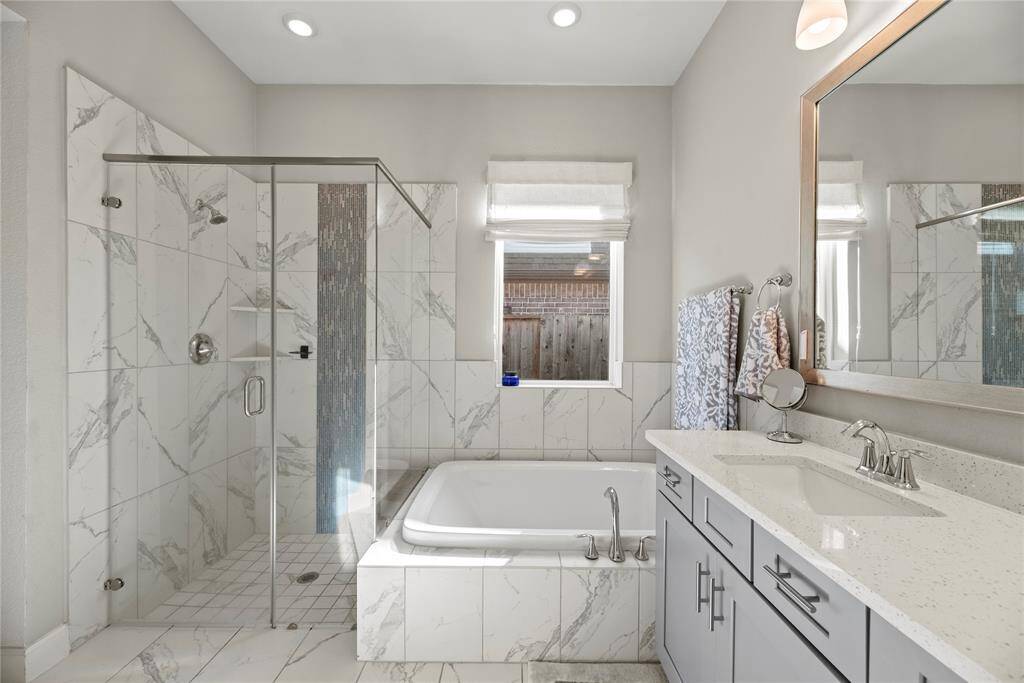 The large walk-in shower, adorned with stunning tile work and a sleek glass front, offers a luxurious escape for a quick rinse or a refreshing retreat.