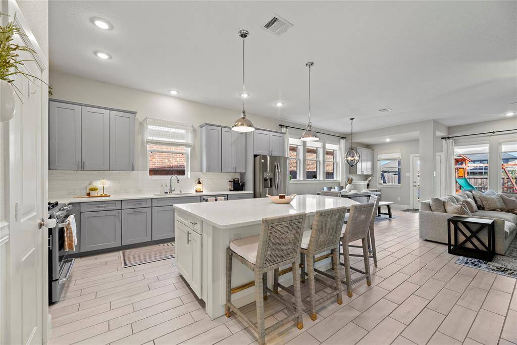 Your chef inspired kitchen awaits! Features include quartz countertops paired with a coordinating tile backsplash, stainless steel appliances, richly painted cabinets with updated hardware, recessed lighting, pendant lights and a sprawling island with breakfast bar seating.