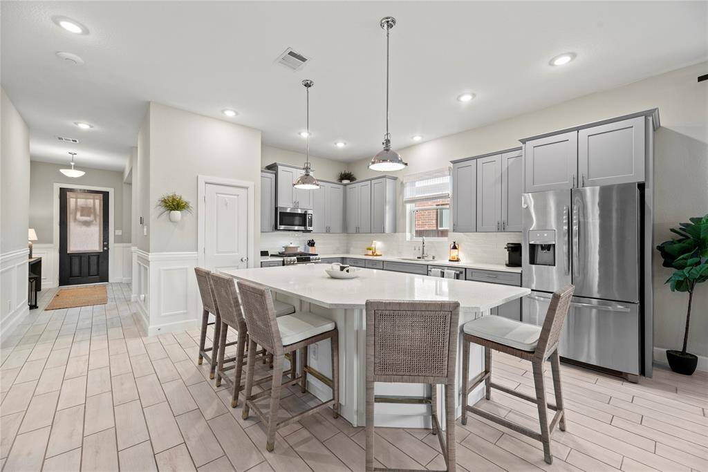 Quartz countertops paired with a coordinating backsplash not only provide a durable and elegant surface for food preparation but also add a touch of luxury and sophistication to the kitchen.