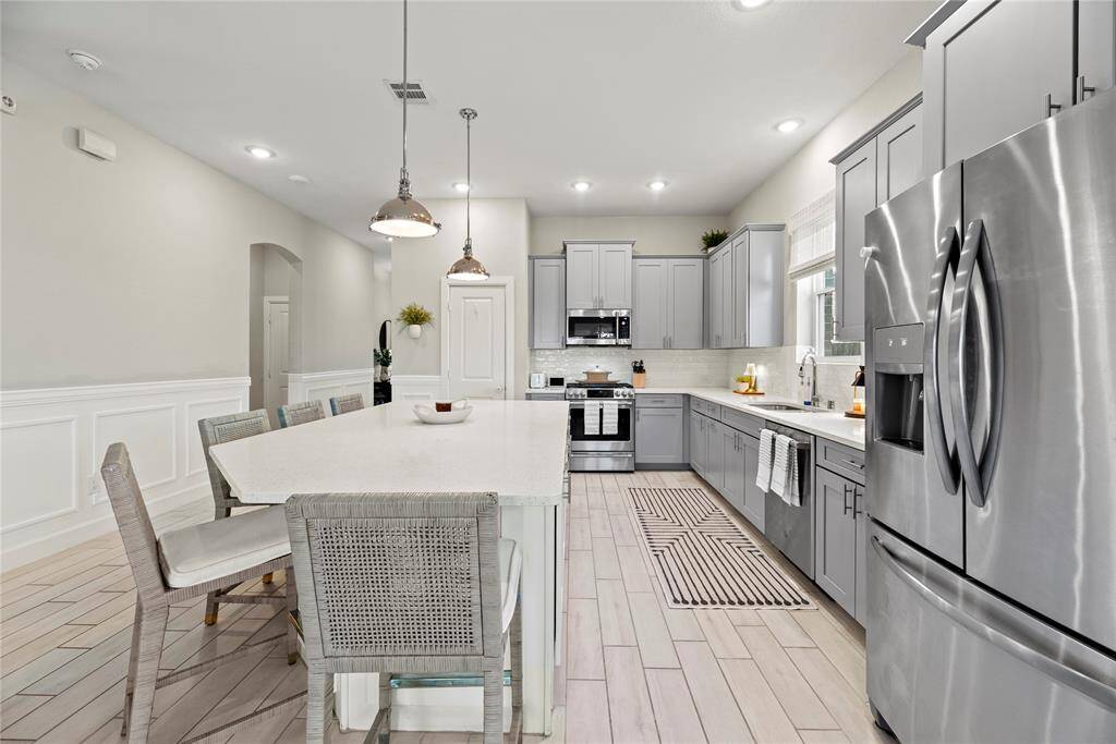 The sprawling island with breakfast bar seating serves as a versatile centerpiece, providing additional workspace, storage, and seating for casual dining or entertaining.