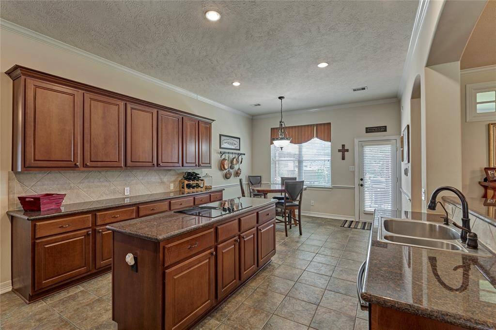 The island kitchen features quality stained cabinets, granite countertops, and ample storage space.
