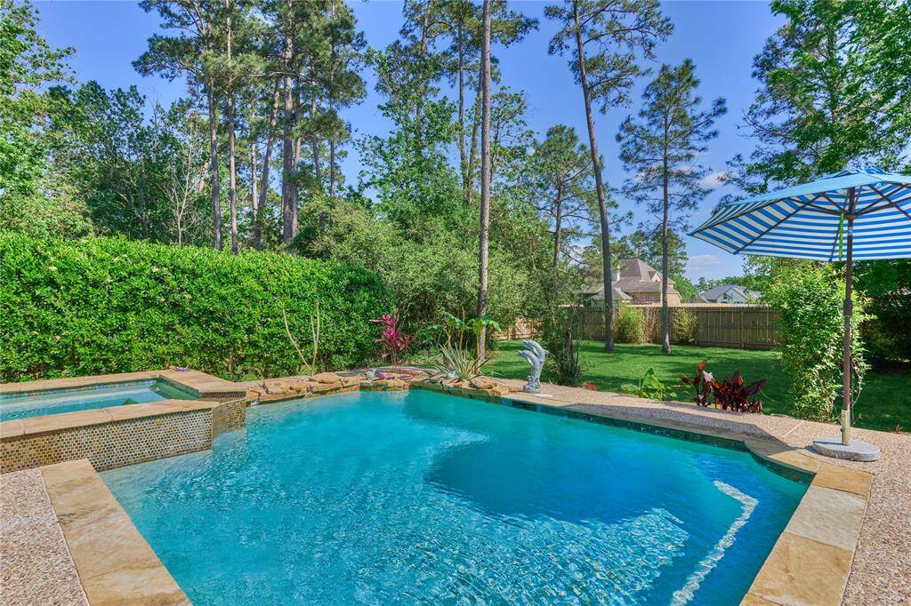 The property features a shimmering pool and spa, surrounded by vibrant landscaping.