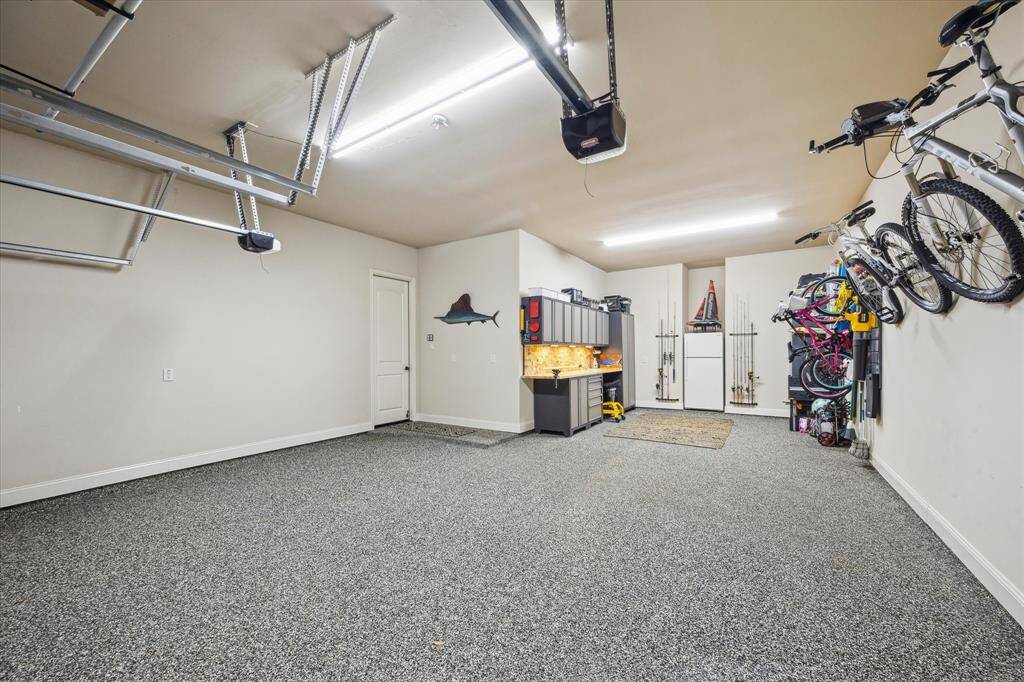 Plenty of space for vehicles and storage with work bench and cabinetry.