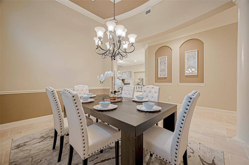 The formal dining room exudes elegance with a stunning chandelier, a delightful tray ceiling, and stately pillars, creating the perfect setting for memorable meals and gatherings.
