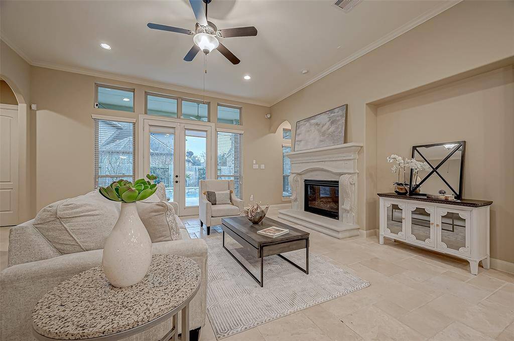 The relaxing family room is bathed in natural light from a stunning wall of windows and elegant French doors, seamlessly connecting to the backyard oasis for the perfect blend of indoor-outdoor living.