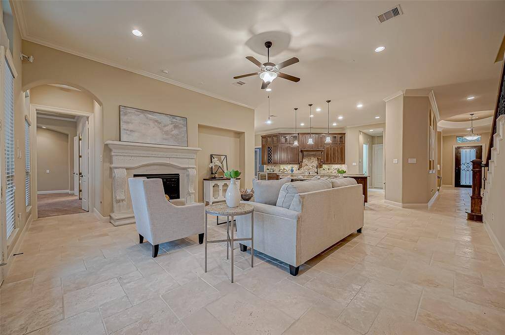 Enjoy the expansive space designed for both entertaining and relaxation—cozy up by the elegant cast stone fireplace or stay cool under the breeze of the ceiling fan, creating year-round comfort.