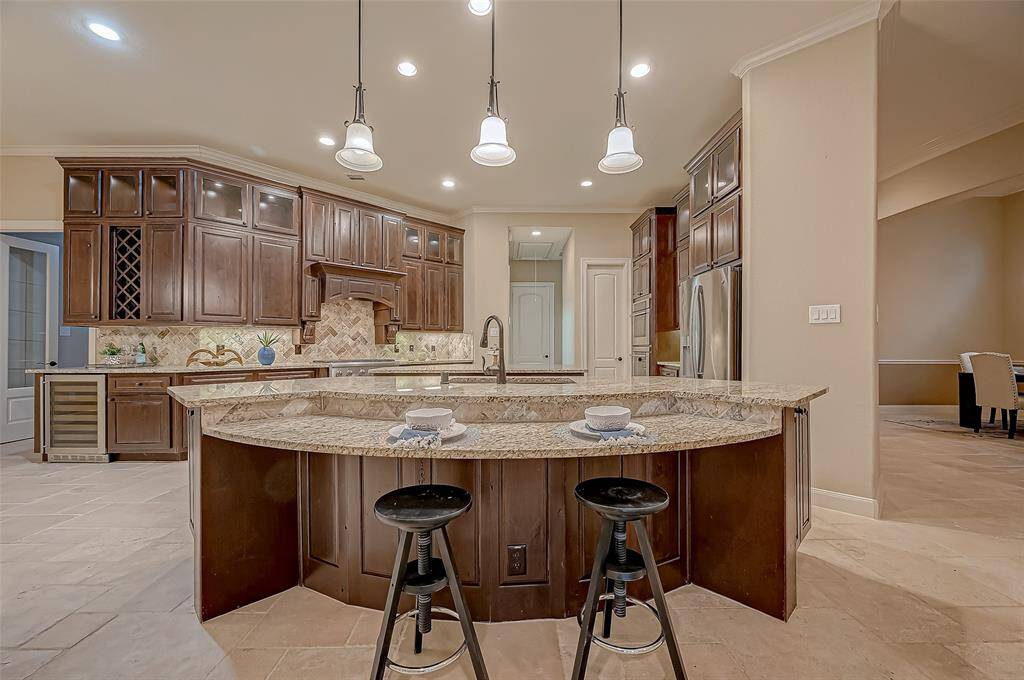 Welcome to the heart of this luxurious home! Enjoy a light bite at the stunning breakfast bar, beautifully illuminated by the warm glow of elegant pendant lights. This gourmet kitchen opens to the breakfast nook and family room.