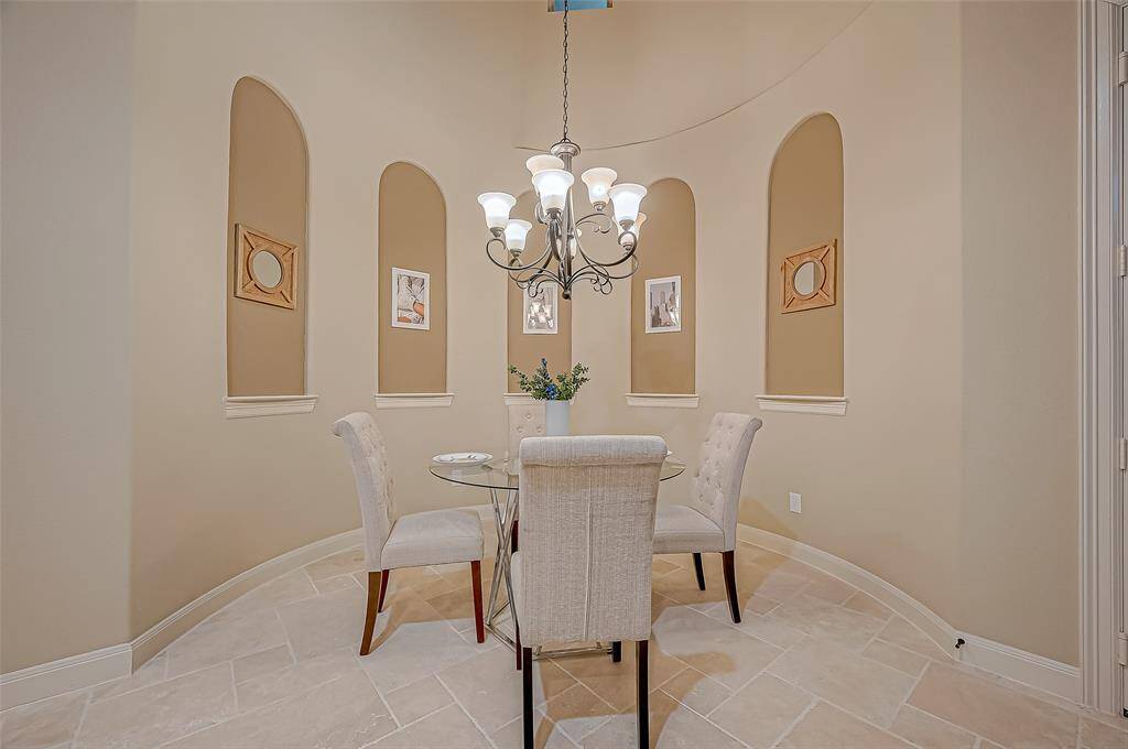 The breakfast alcove boasts a unique architectural design, featuring elegant art niches along the curved wall and a beautiful chandelier that adds a touch of sophistication to the space.