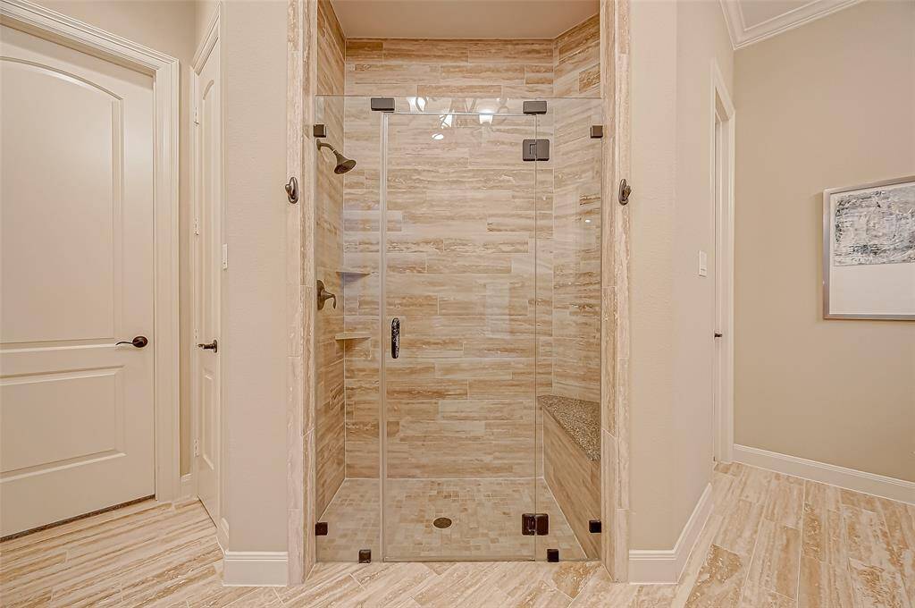 The sleek glass-front shower features stunning floor-to-ceiling tile and a built-in seat, offering both style and comfort for a spa-like experience.