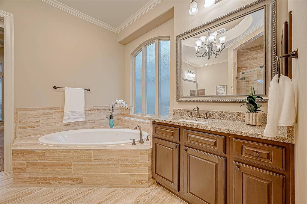 Soothe your cares away in this fabulous tub, bathed in natural light and the warm glow of a chandelier, all framed by an elegant tray ceiling for a truly luxurious retreat.