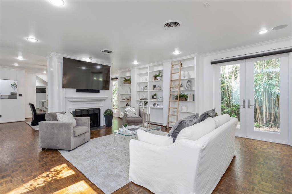Alternate view of the large living room. Entry way leads straight into the formal living area with beautiful shelving and fire place. Notice the beautiful wood flooring.