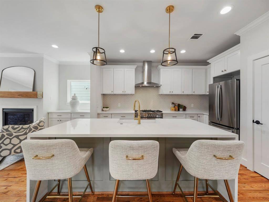 Chef-inspired kitchen boasting a striking quartz waterfall island that takes center stage. The sleek stainless steel appliances are paired with custom cabinetry, providing ample storage and style. Under-cabinet lighting highlights the elegant finishes, creating a bright and inviting space for cooking and entertaining. The open layout enhances both functionality and design.