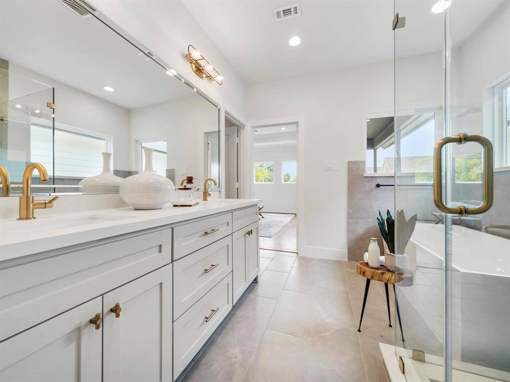 Luxurious ensuite bathroom featuring dual sinks with modern fixtures, a relaxing soaking tub for ultimate comfort, and a spacious walk-in shower with sleek design elements. The spa-like atmosphere offers a perfect place to unwind, complete with designer finishes and plenty of storage.
