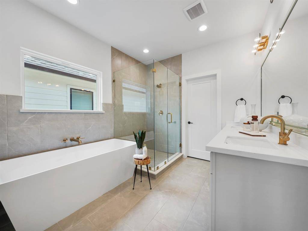 Luxurious ensuite bathroom featuring dual sinks with modern fixtures, a relaxing soaking tub for ultimate comfort, and a spacious walk-in shower with sleek design elements. The spa-like atmosphere offers a perfect place to unwind, complete with designer finishes and plenty of storage.