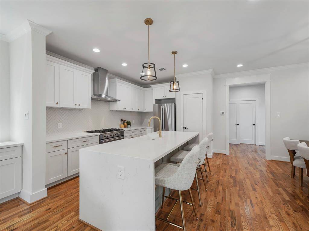 Modern and elegant kitchen featuring a stunning quartz waterfall island that serves as a stylish focal point. Sleek stainless steel appliances complement the contemporary design, while ample cabinetry provides both functionality and storage. The open layout and high-end finishes make this kitchen perfect for cooking and entertaining.