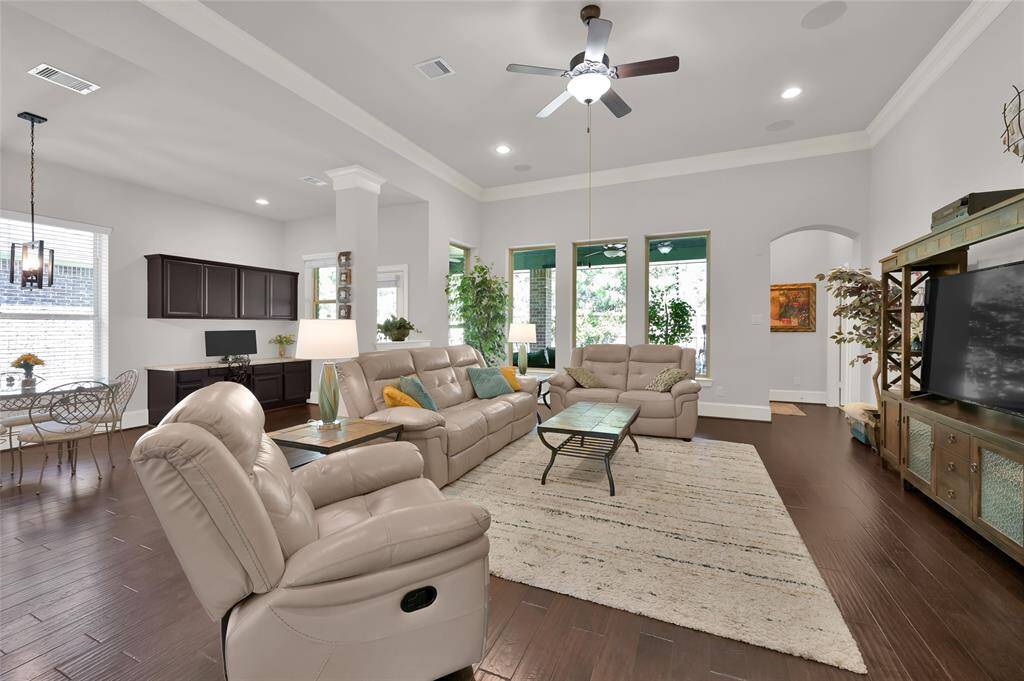 Spacious living area with high ceilings, with plenty of room for comfortable seating arrangements. Large windows offer natural light, while hardwood floors and a neutral color palette enhance the elegance. Adjacent dining area and built-in shelving add functionality. Perfect for entertaining and relaxation.