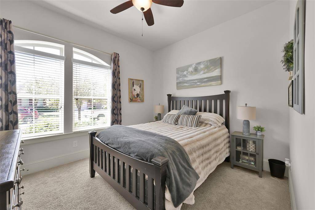 This third bedroom features a large window, allowing plenty of natural light. It includes a stylish ceiling fan, a plush carpet.