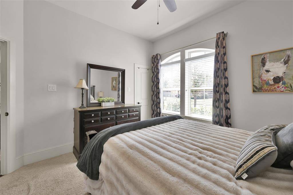 This third bedroom features a large window, allowing plenty of natural light. It includes a stylish ceiling fan, a plush carpet.