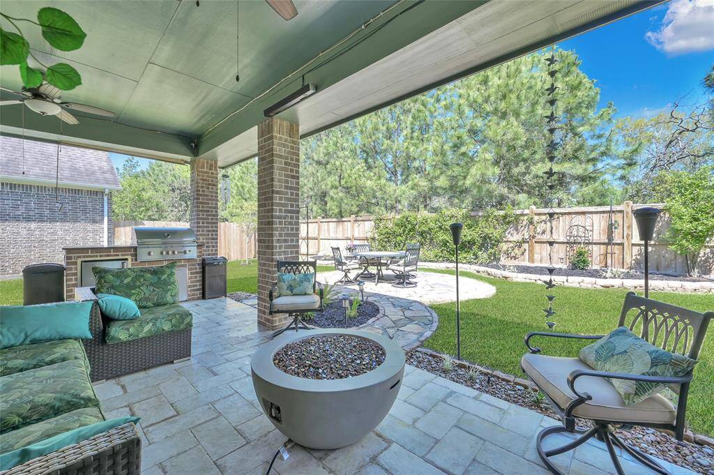 Check out this spacious, covered patio with plenty of room for comfortable seating, an outdoor ceiling fan, and a built-in grill. The patio opens to a well-maintained backyard featuring, a paved seating area, and a privacy fence lined with trees, ideal for outdoor entertaining.